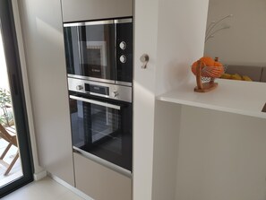 A modern kitchen with a built-in Bosch oven, a white countertop, and a wooden decorative item.