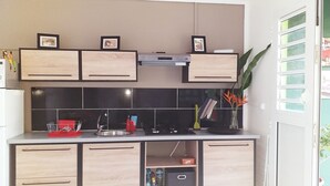 Una cucina moderna con pensili in legno, zoccolo a mosaico nero e piano cottura integrato.