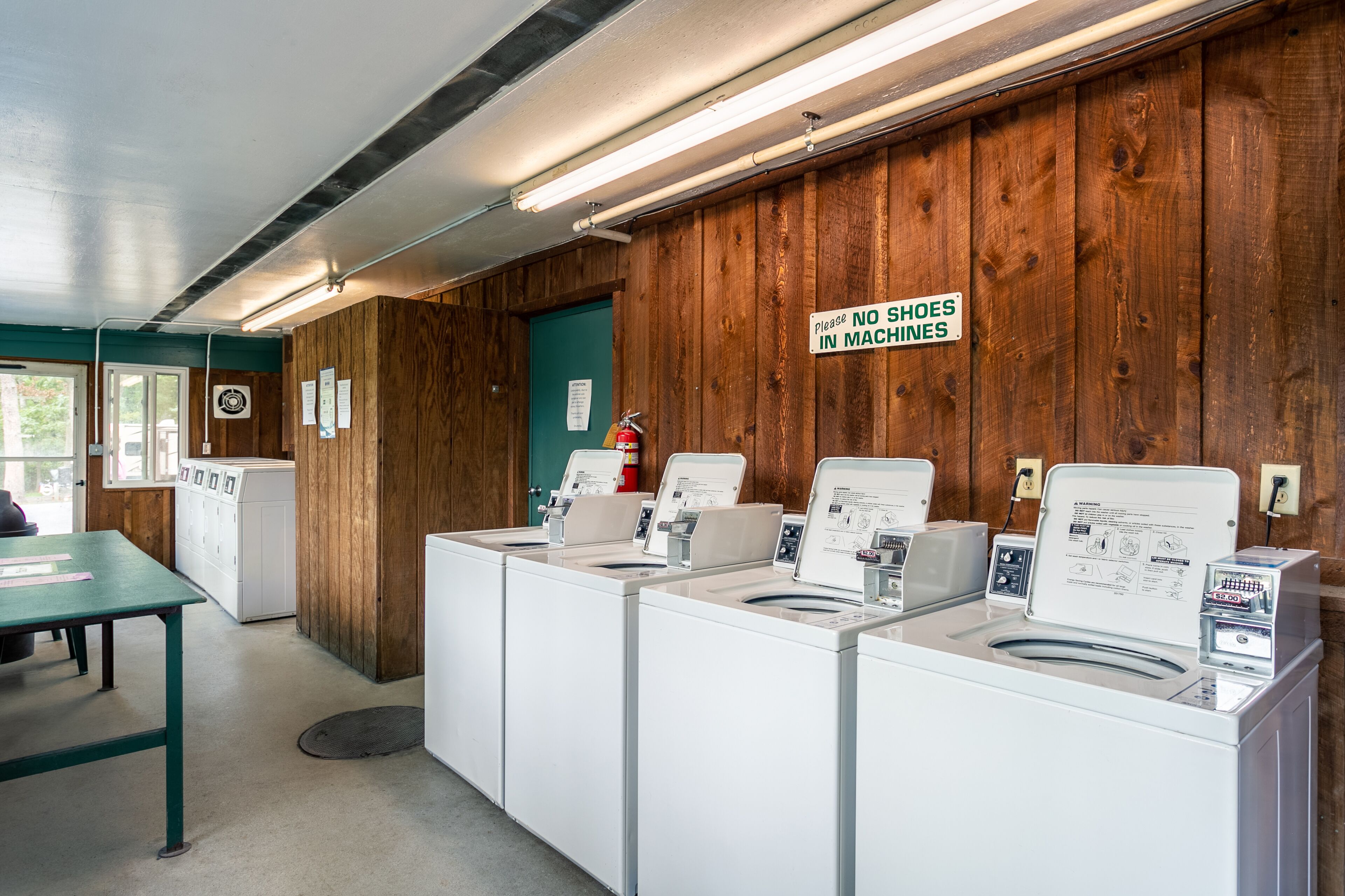A laundry area with multiple washing machines and a table.