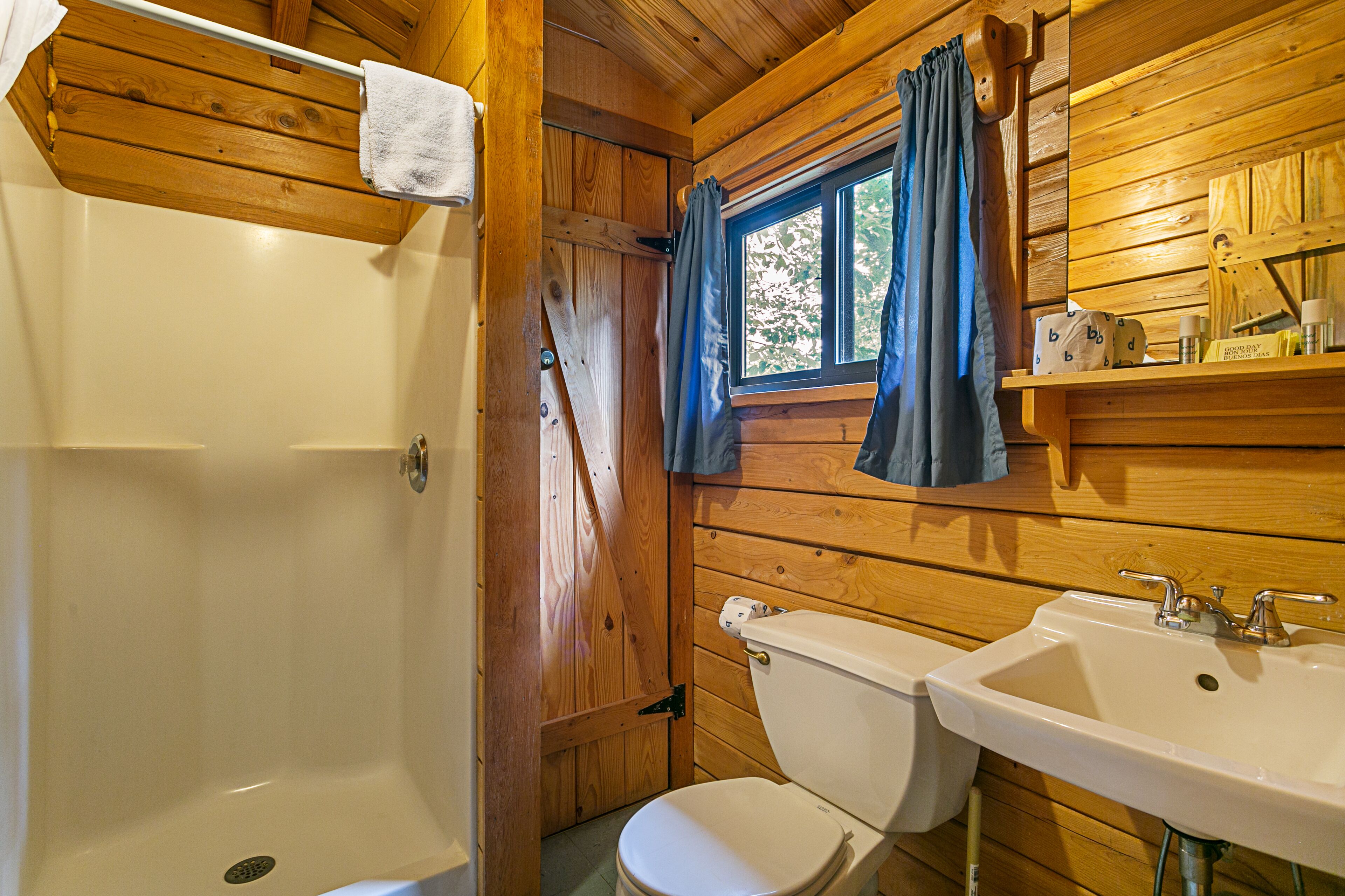 Un baño de cabaña de madera con bañera, inodoro y lavamanos.