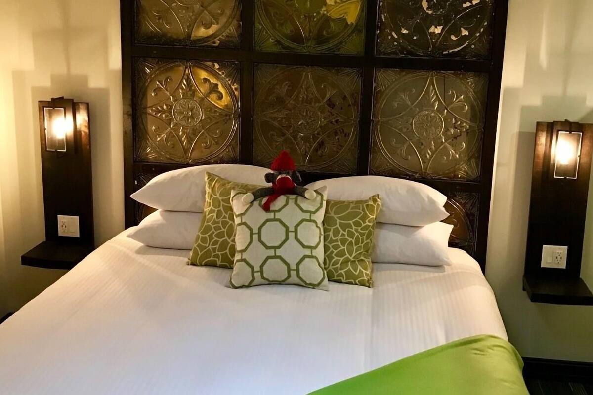 A neatly made bed with patterned pillows and a decorative headboard.