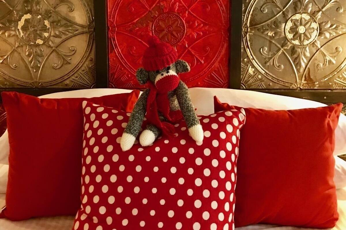 A bed with red polka dot pillows and a teddy bear.