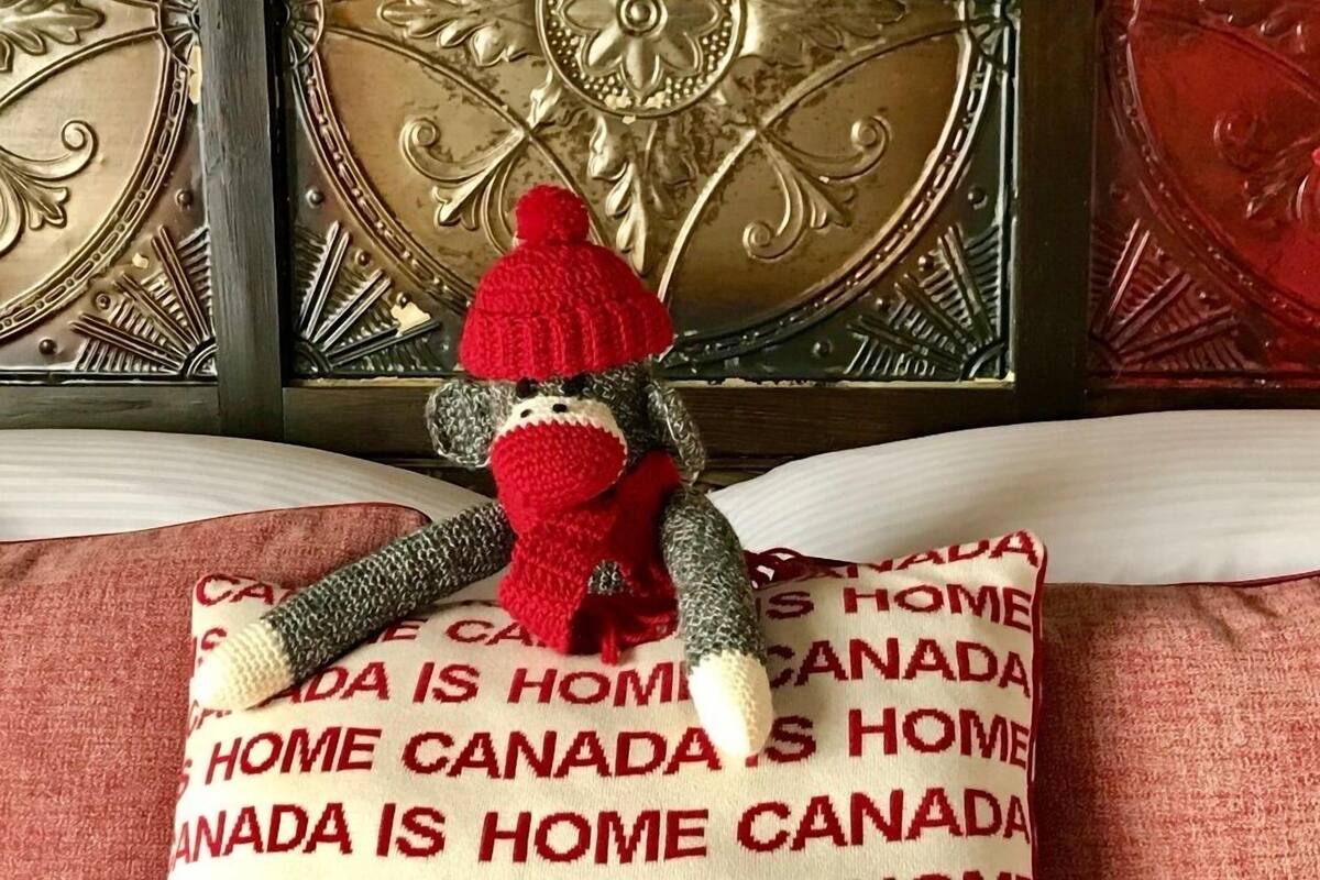 A plush toy on a pillow with "CANADA IS HOME" text.