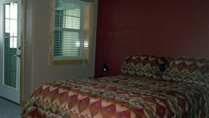 A bedroom with a bed, a window with blinds, and a door.