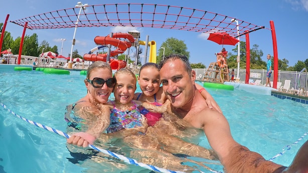 A swimming pool with a water slide and a netted play area. - Bethpage Camp-Resort (Urbanna)