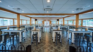 A spacious restaurant with multiple tables and chairs, large windows, and a tiled floor. - Bethpage Camp-Resort (Urbanna)