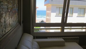 A room with a view of the sea through a window, a radiator, and a white sofa. - Front line with sea views garage + free wifi (Zarauz)
