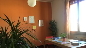 A room with a wooden table, chairs, a potted plant, and a window with curtains. - Casa Arcobaleno, an experience to try! (Firenze)