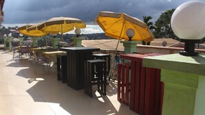 An outdoor seating area with yellow umbrellas, tables, and chairs. - Complexe Hotelier St Elie (Yaoundé)