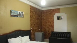 A hotel room with a bed, a small desk, a chair, and a cabinet. - Complexe Hotelier St Elie (Yaoundé)