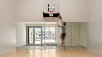 A basketball hoop in a modern indoor space with a glass partition and a bench.