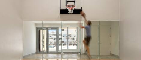 A basketball hoop in a modern indoor space with a glass partition and a bench.