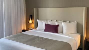 A hotel room with a large bed, a nightstand with a lamp, and a window with curtains.