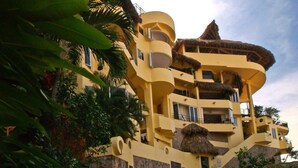 Un edificio de varios pisos con fachada amarilla, balcones y techo de paja.