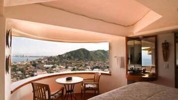 Habitación de hotel con balcón, cama, una mesita y sillas.