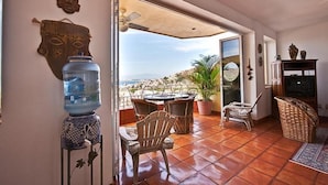 Habitación con zona de patio amueblada con mesa y sillas, un dispensador de agua y elementos decorativos.