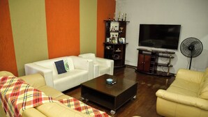 A living room with two white sofas, a coffee table, a TV, and a trophy shelf. - CHÁCARA BELLA VITTA <br>WANT COMFORT, PEACE, SECURITY. A HEATED POOL. HE COMES. (socorro)