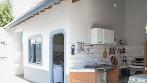 A compact kitchen with a built-in island, white cabinets, and a dining area with a table. - CHÁCARA BELLA VITTA <br>WANT COMFORT, PEACE, SECURITY. A HEATED POOL. HE COMES. (socorro)