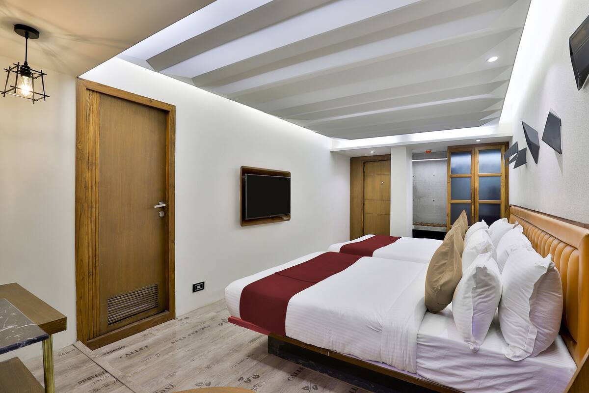 A hotel room with a large bed, a television mounted on the wall, and a wooden door.