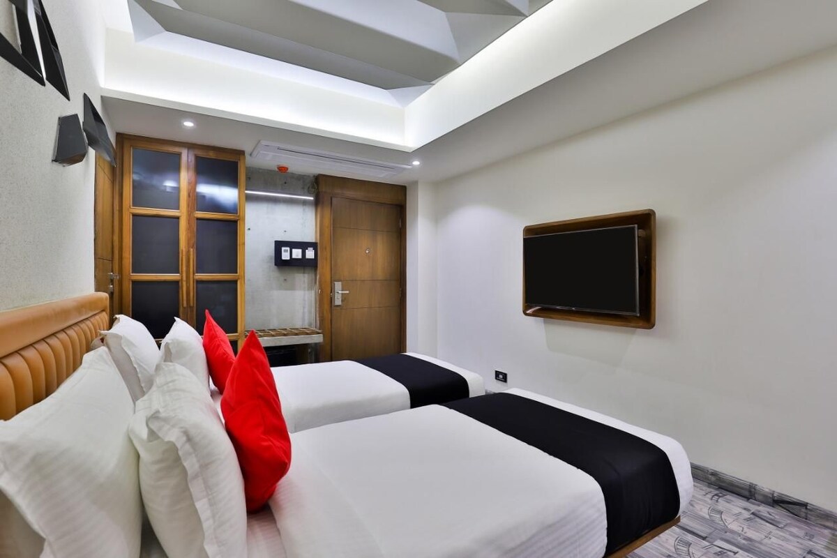 Une chambre d’hôtel avec deux lits, une télévision, une armoire en bois et une lucarne.