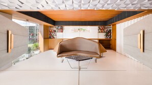 Een modern interieur met een geometrisch plafond, een centraal zitgedeelte en boekenkasten.