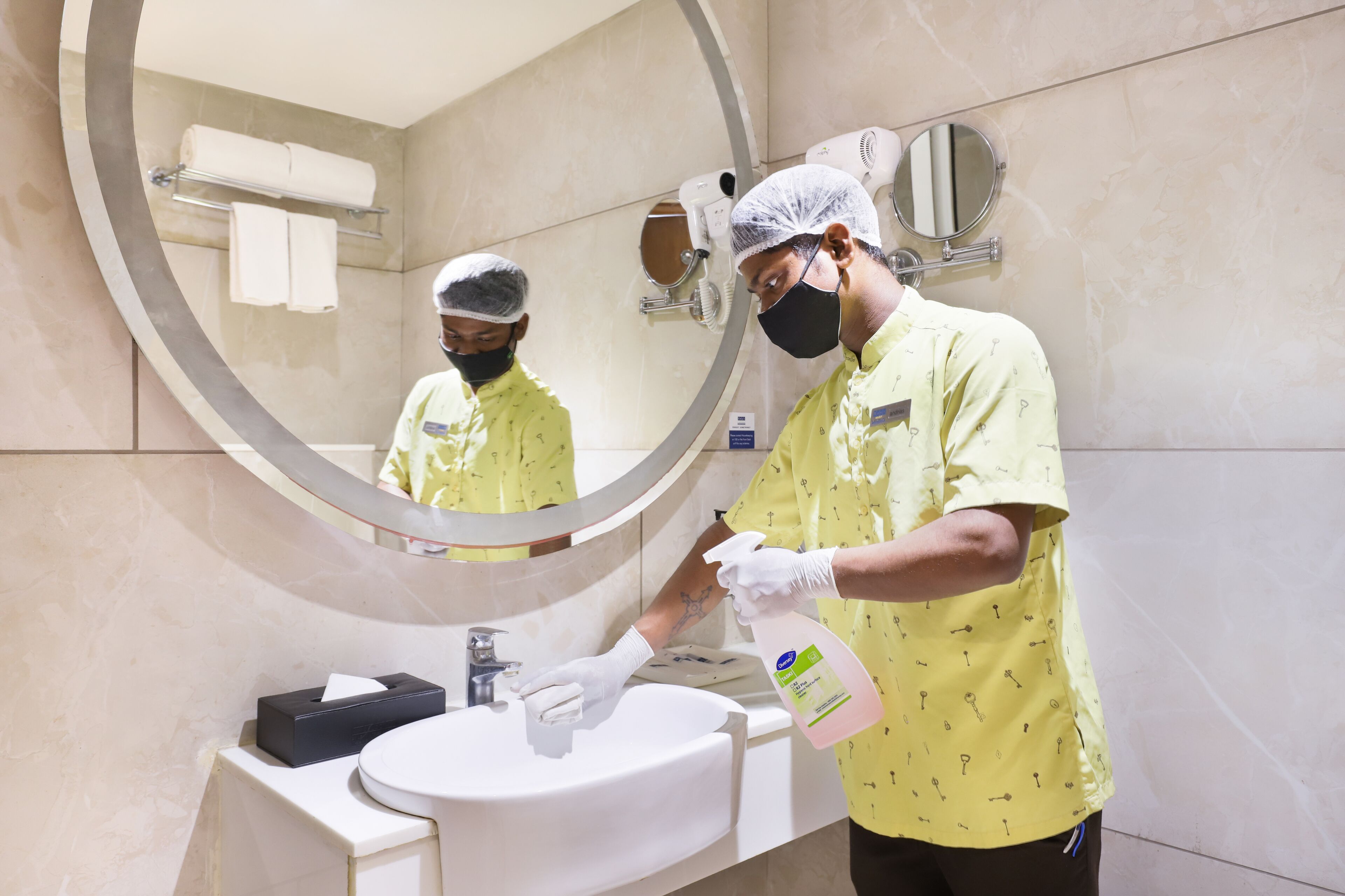 A person cleaning a bathroom sink with a spray bottle.