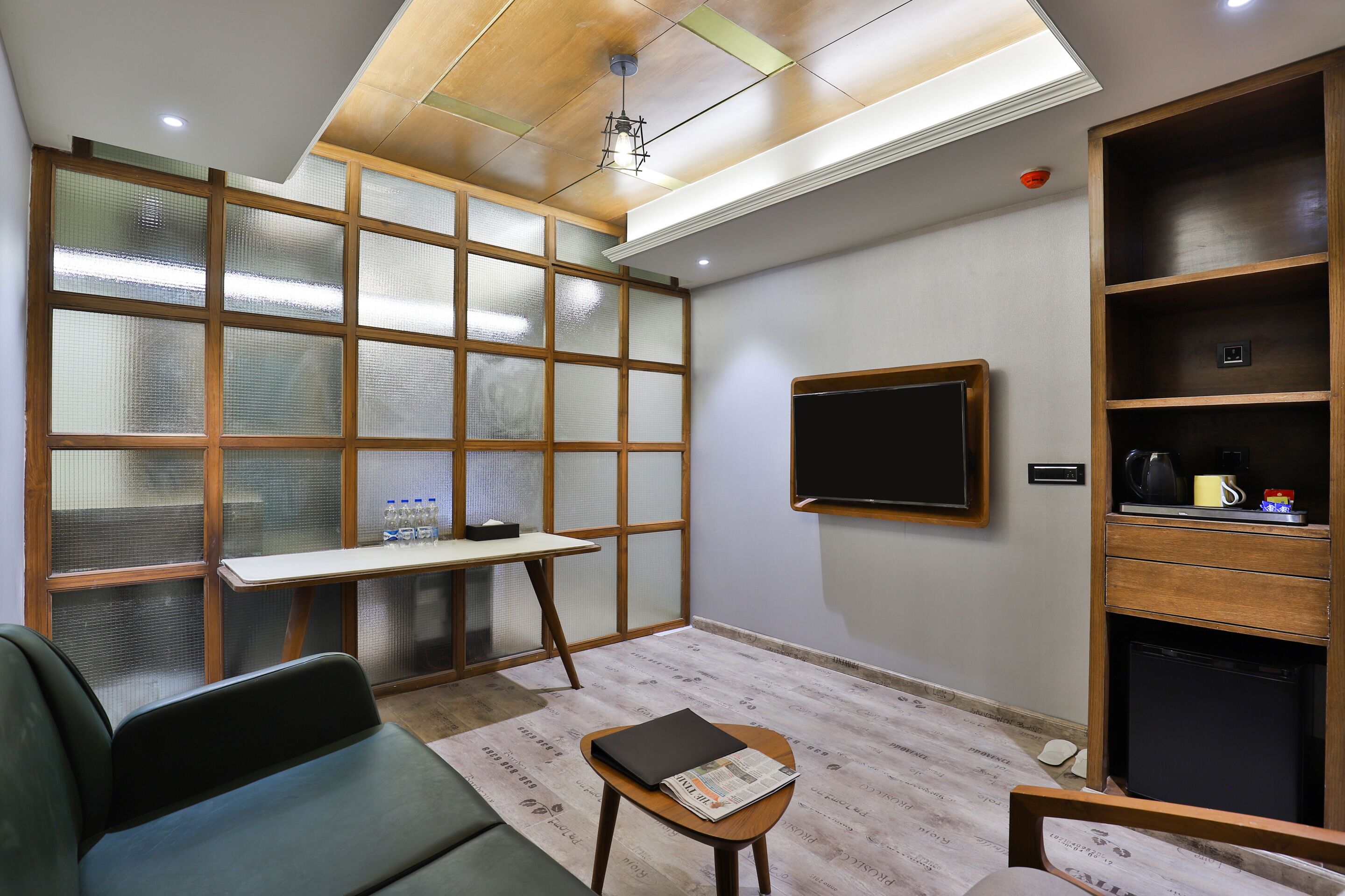 Une chambre moderne avec un canapé, une petite table sur laquelle se trouvent un livre et un journal, un meuble en bois et une grande fenêtre donnant sur un beau paysage.