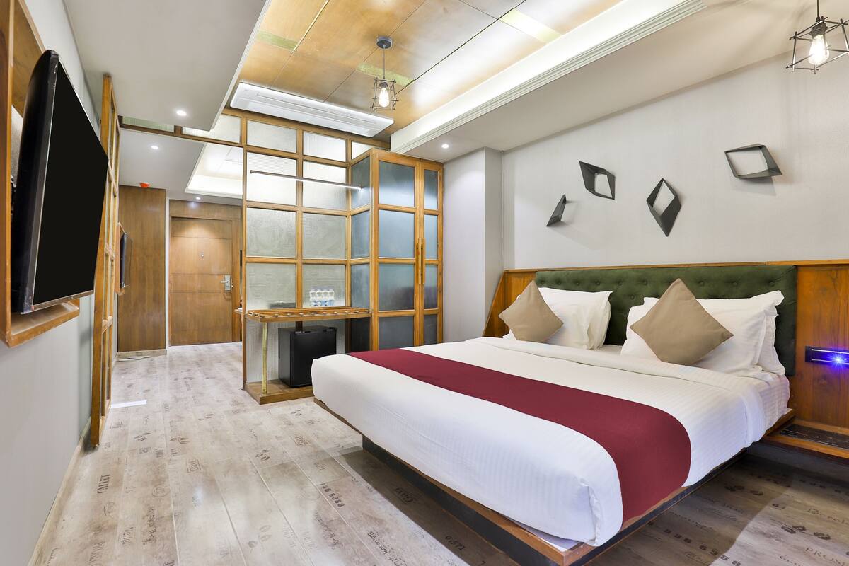 A hotel room with a large bed, a wardrobe, a desk, and a television.