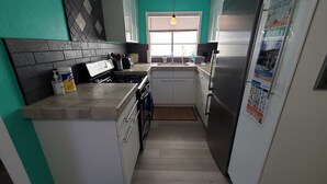 Eine kleine Küche mit Herd, Spüle und Kühlschrank.