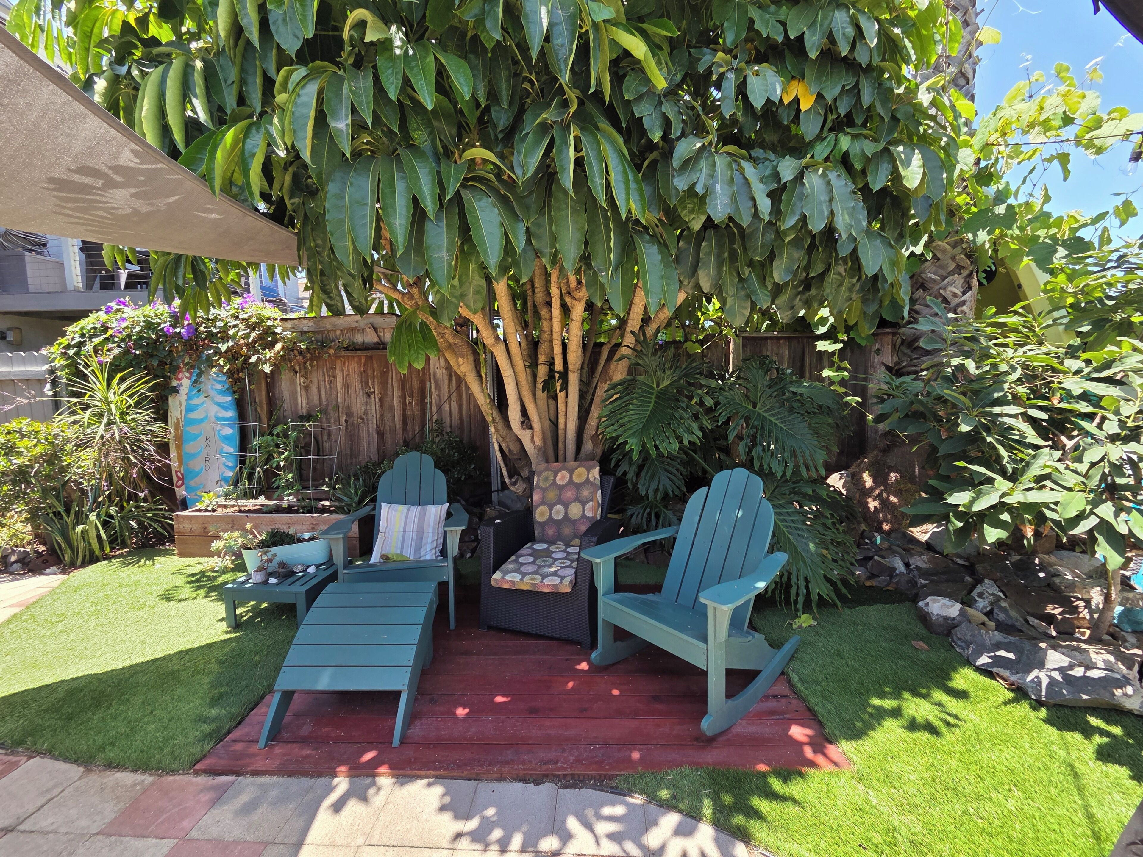 A patio with two Adirondack chairs, a small table, and a potted plant.
