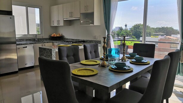 A modern kitchen with a dining area, featuring a large window with a view of the city. - Condo  Blanca!!!!!!! (Nuevo Vallarta)