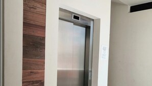 An elevator with a metallic finish, adjacent to a wall with a wooden panel design. - Condo  Blanca!!!!!!! (Nuevo Vallarta)