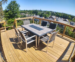 A wooden deck with a table and chairs, overlooking a residential area.