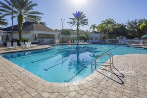 A swimming pool with clear blue water, surrounded by lounge chairs and palm trees. - Our Quiet Retreat by VillaDirect (Kissimmee)