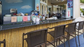 An outdoor bar area with a counter, bar stools, and various items on the counter. - Our Quiet Retreat by VillaDirect (Kissimmee)