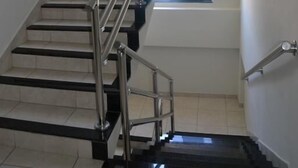 Un escalier avec des rampes en métal, une fenêtre en haut et une vue sur une voiture à l’extérieur.