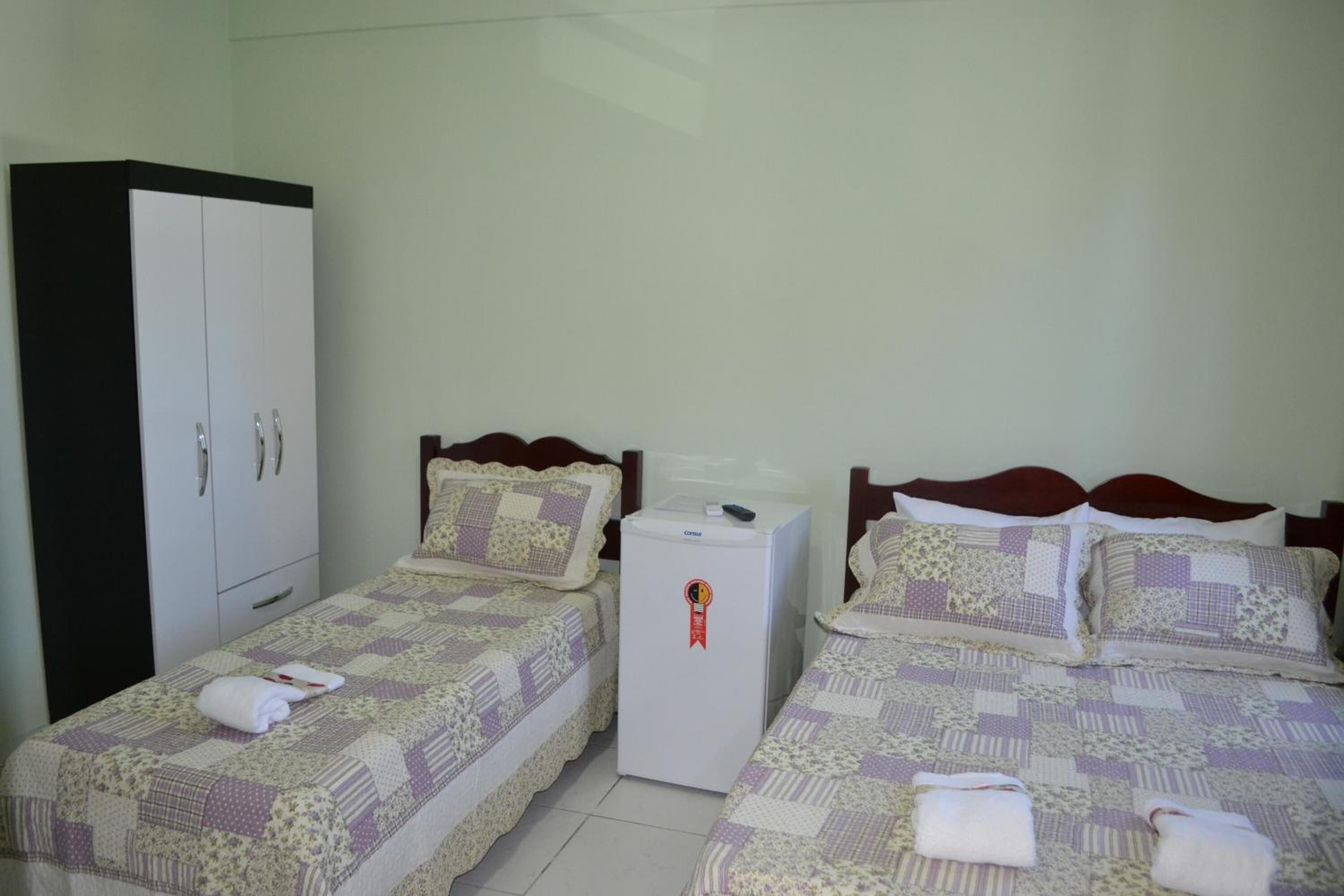 Quarto de hotel com duas camas, um guarda-roupa e um minibar.