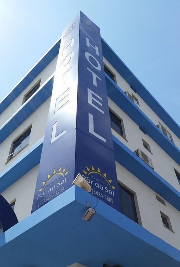 A hotel building with a prominent vertical sign displaying the word "HOTEL" and a logo with a sun and the text "Pôr do Sol". - Palace Hotel Por do Sol (Vitoria da Conquista)