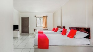 A hotel room with two beds, a TV, a desk, and a window with curtains. - OYO Hotel Jaguar (Cancun)