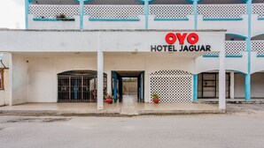 The exterior of OYO Hotel Jaguar with a white facade, blue accents, and a gated entrance. - OYO Hotel Jaguar (Cancun)