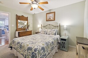 A bedroom with a bed, a nightstand, a dresser, a mirror, a ceiling fan, and a painting on the wall. - Welcome to “Relax Inn” Retreat at Lake Cumberland – A Perfect Cabin Escape (Burnside)