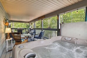 A hot tub on a covered deck with outdoor furniture and a view of trees. - Welcome to “Relax Inn” Retreat at Lake Cumberland – A Perfect Cabin Escape (Burnside)