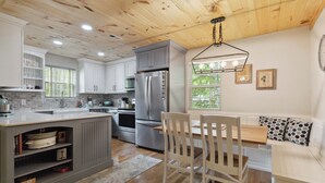 A modern kitchen with a central island, stainless steel appliances, and a wooden ceiling. - Welcome to “Relax Inn” Retreat at Lake Cumberland – A Perfect Cabin Escape (Burnside)