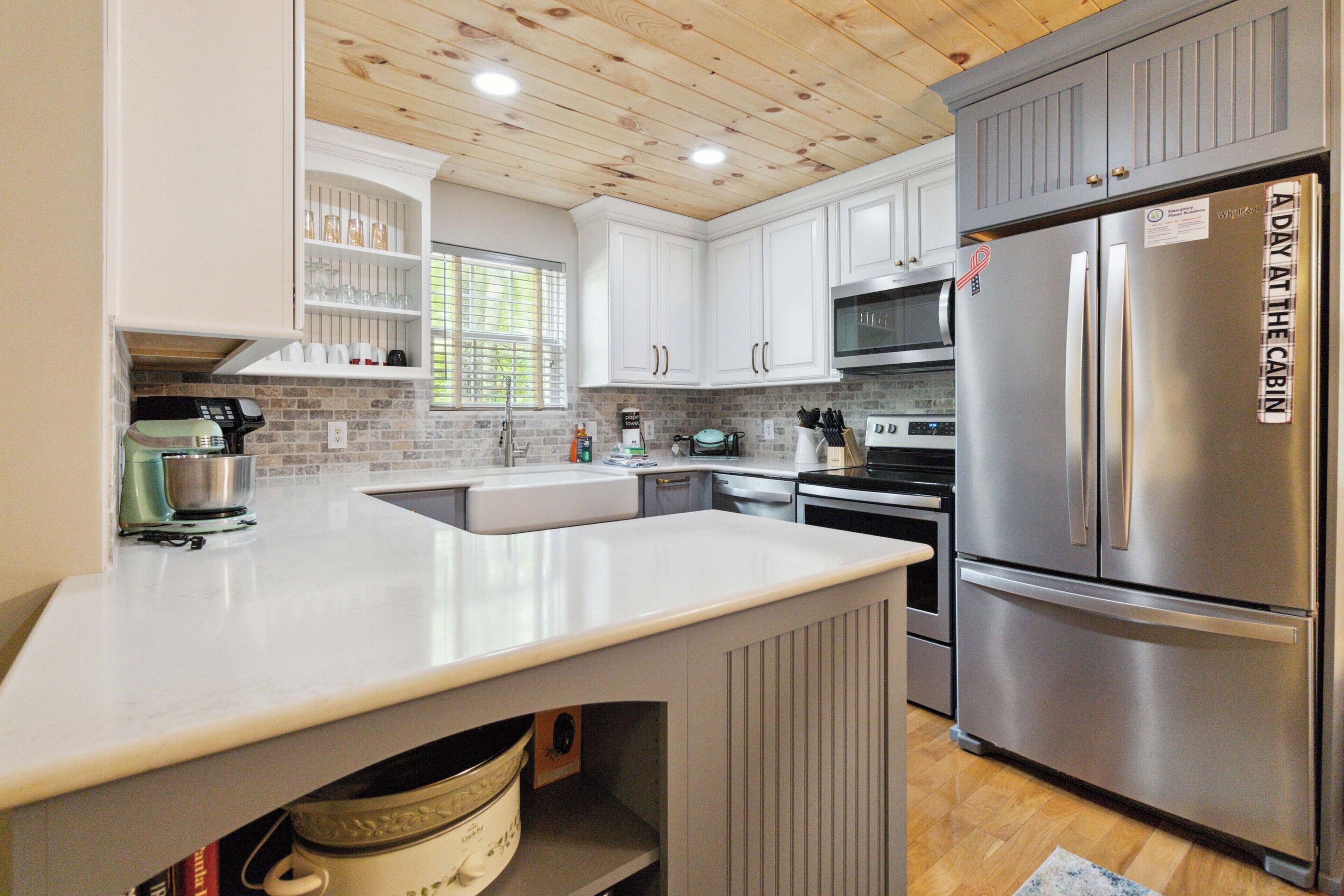 A modern kitchen with white cabinetry, a stainless steel refrigerator, and a built-in oven.