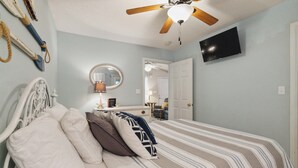 A bedroom with a bed, a ceiling fan, a TV, and a door leading to another room. - Welcome to “Relax Inn” Retreat at Lake Cumberland – A Perfect Cabin Escape (Burnside)