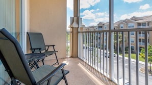 A balcony with two chairs, a view of a residential area, and a clear sky. - Summer Settings by VillaDirect (Kissimmee)