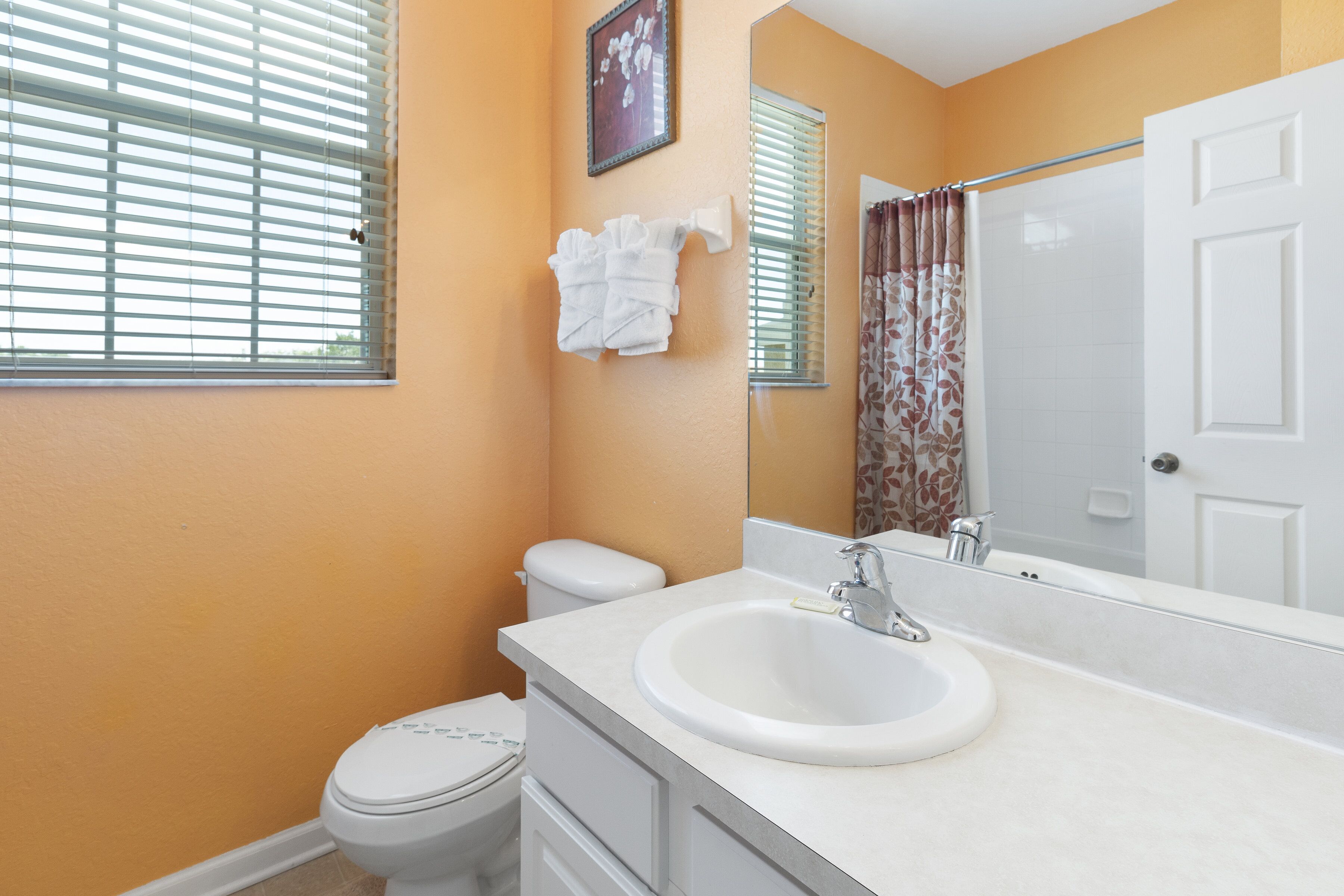 A bathroom with a white toilet, a sink with a mirror, and a shower curtain.