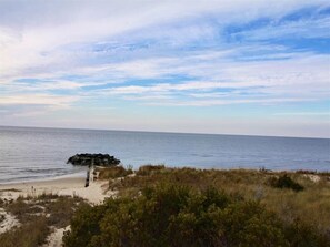 A beach with a rocky outcrop and a wooden walkway leading to the water.