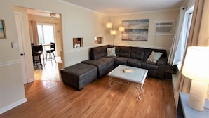A living room with a sectional sofa, a coffee table, and a dining area visible through an open door. - Pet friendly cottage by the Delaware Bay-Townbank  (Townbank)