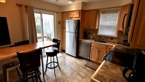A kitchen with wooden cabinets, a stainless steel refrigerator, a dishwasher, and a coffee maker. - Pet friendly cottage by the Delaware Bay-Townbank  (Townbank)